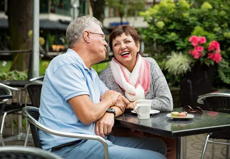 Senior couple in love sitting in street cafe, drinking coffee, talking, laughing and having fun. Happy people in retirement concept. | North houston